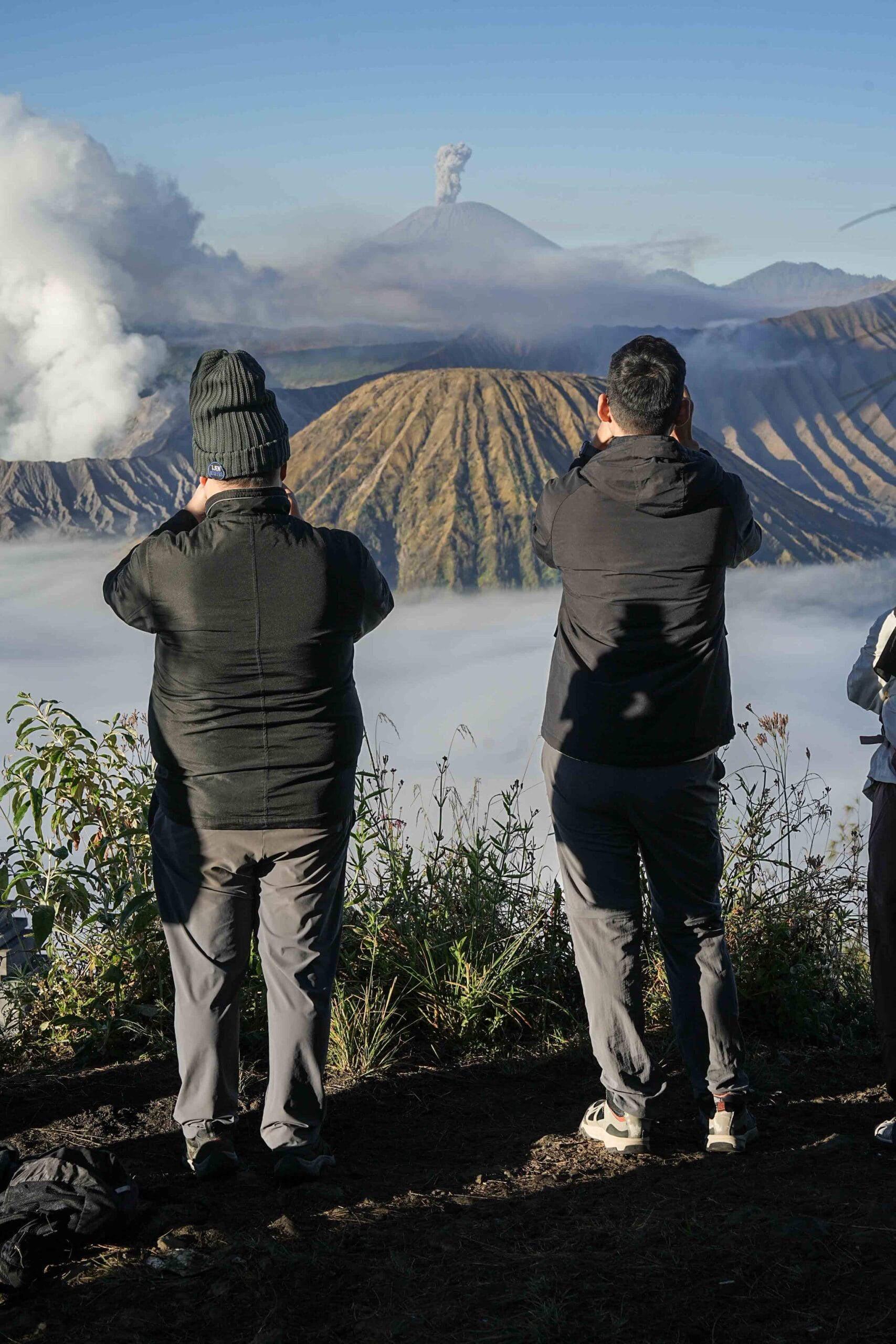 A group of happy travelers hiking near the Mount Bromo crater, showcasing a memorable east java tour guide experience during their volcanic adventure.